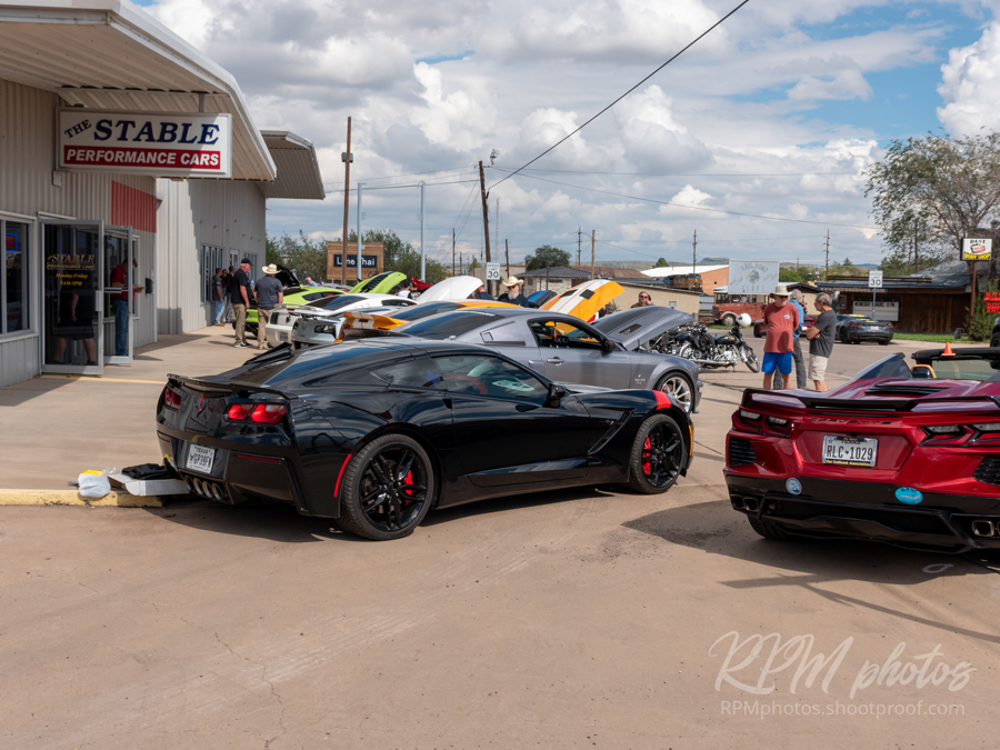 A row of Corvettes and Mustangs parked in front of The Stable Performance Cars during a car show at Octane Fest.