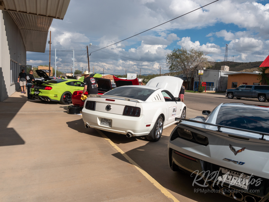 A row of Corvettes and Mustangs parked in front of The Stable Performance Cars during a car show at Octane Fest.