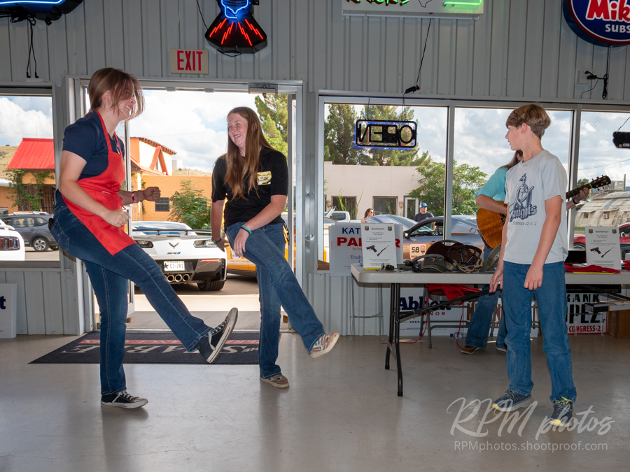 Two girls and a boy dance a funny dance while a woman plays guitar and sings at The Stable Performance Cars during Octane Fest.