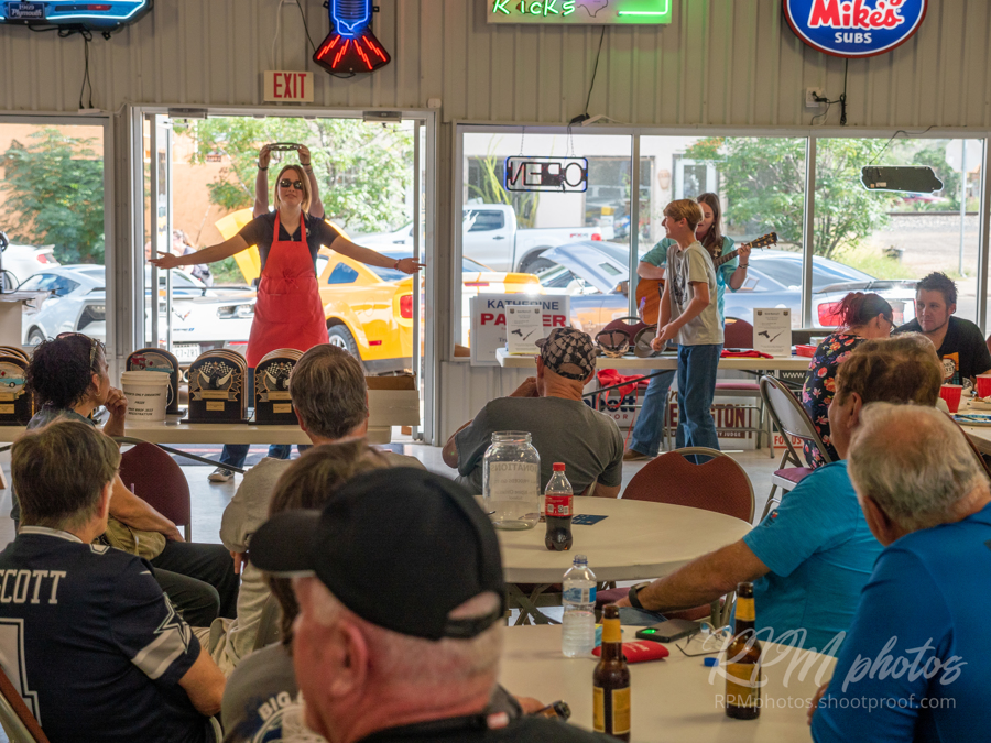 Octane Fest participants listen to a girl singing at The Stable Performance Cars during Octane Fest.